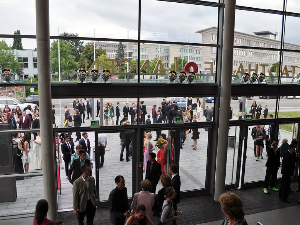 Blick durch die Glasfassade auf die Gäste vor der Halle.